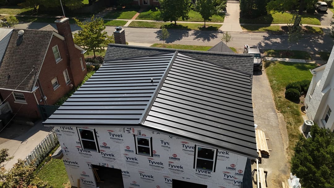 Black standing seam metal roof on a new two story home still in house wrap