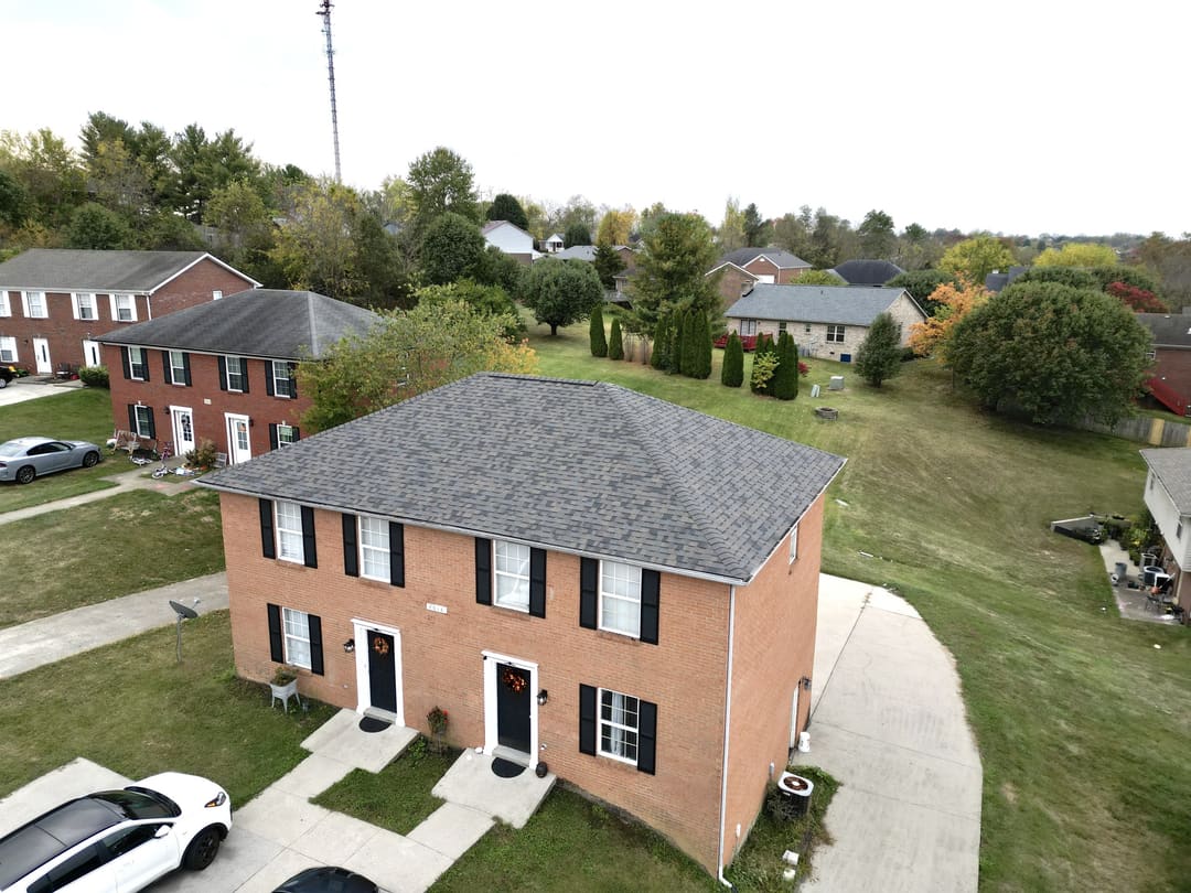 New gray shingle roof on a brick colonial in a neighborhood, seen from the air