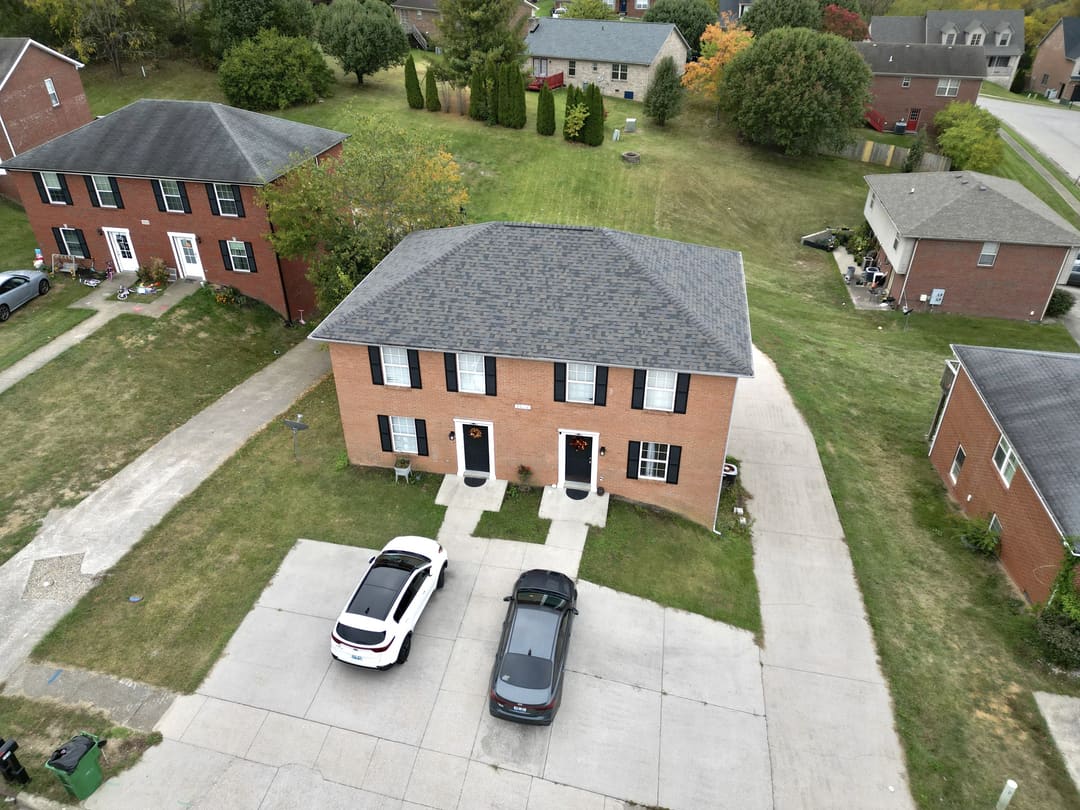 Brick colonial with a new gray shingle roof above its driveway