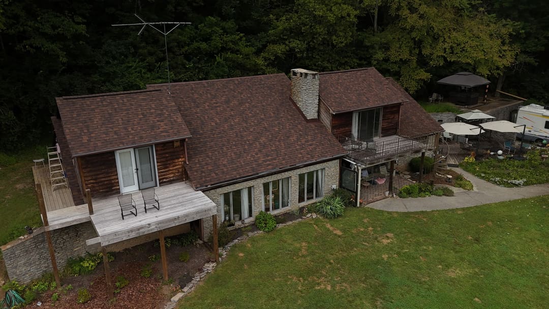 Brown shingle roof on a cedar and stone home with decks, seen from the air