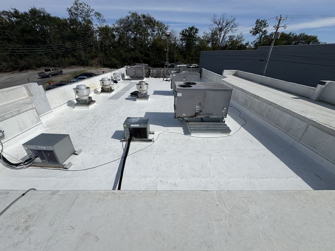 White commercial low-slope membrane roof with rooftop units and parapet walls