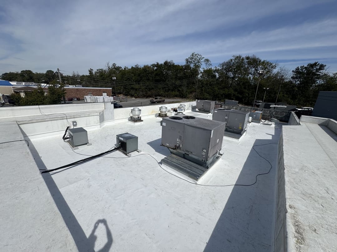 Wide white low-slope membrane roof with rooftop units on a commercial building