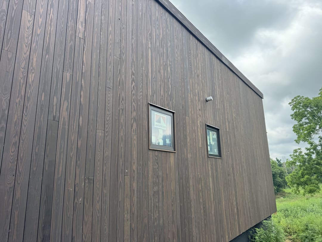 Close view of dark vertical wood siding and a window