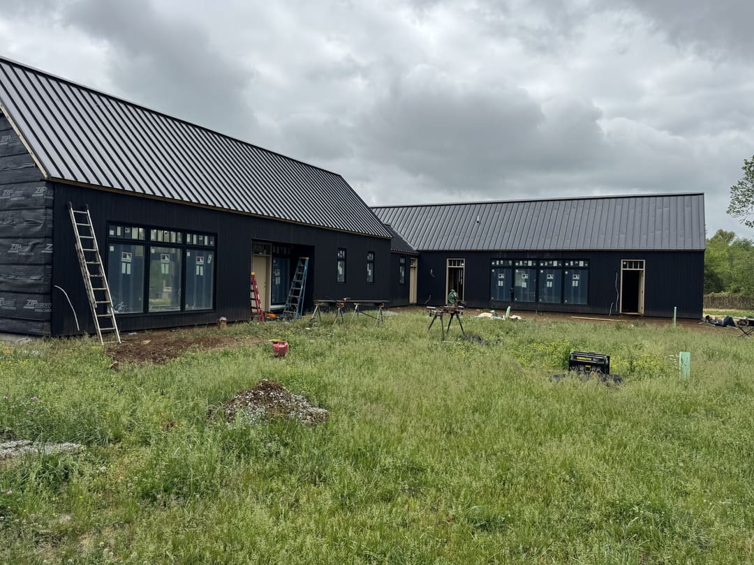 A long modern home in dark wood siding under a black metal roof