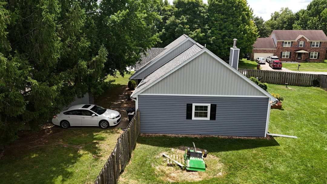 Gray siding and black shutters on a home beside a wood fence, seen from above