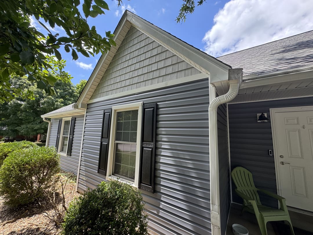 Gray vinyl siding with black shutters and a white gutter