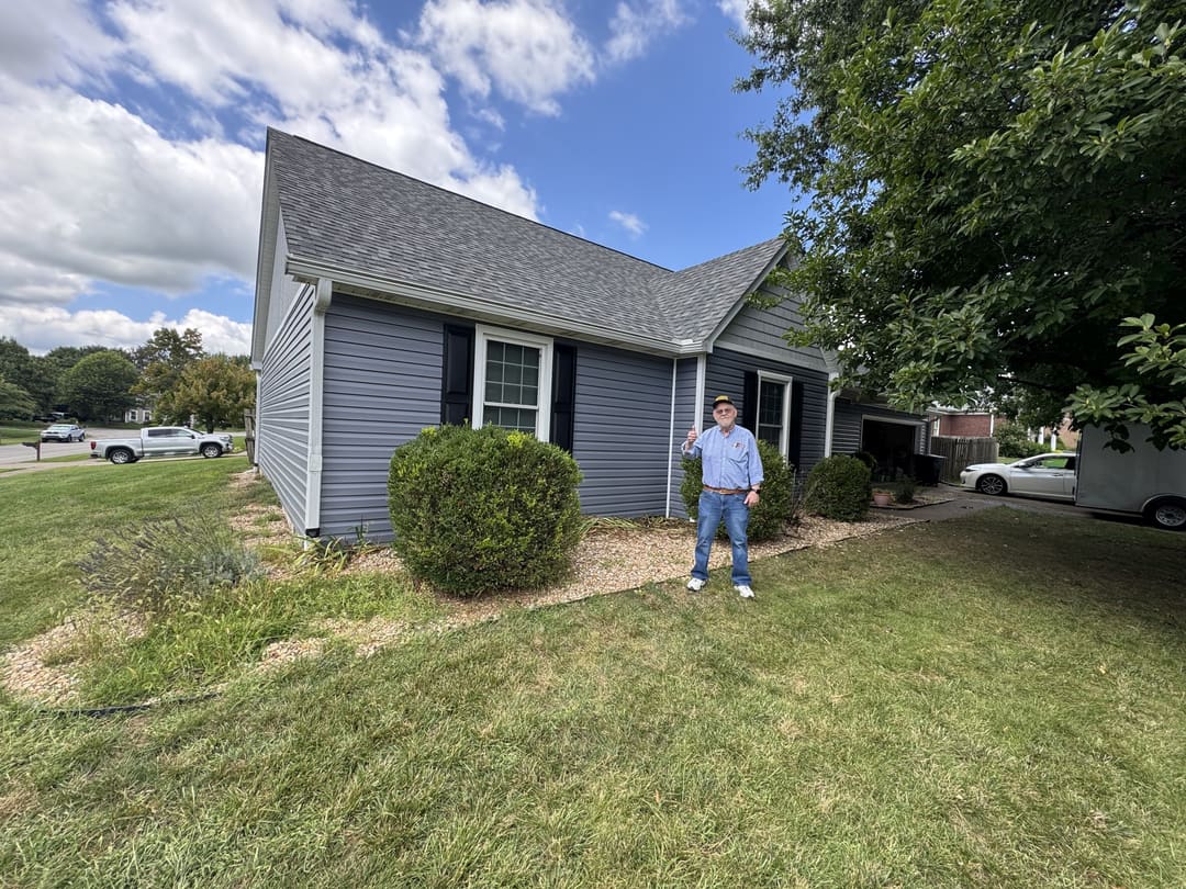 Front of a home finished in gray vinyl siding with black shutters
