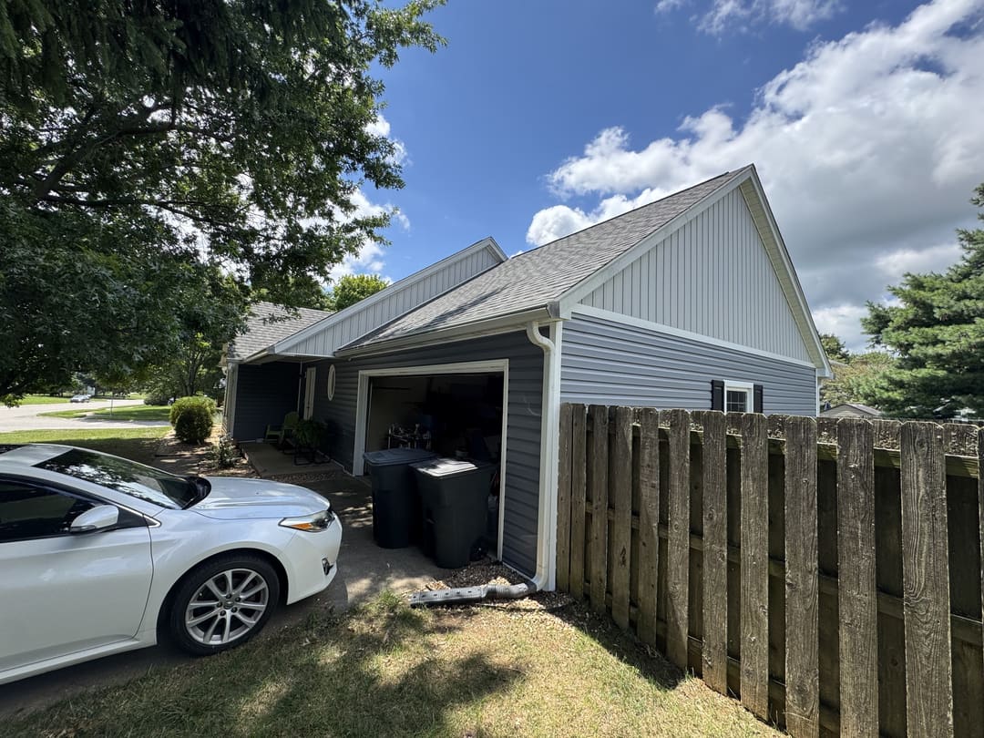 Garage end in gray vinyl siding with a board and batten gable