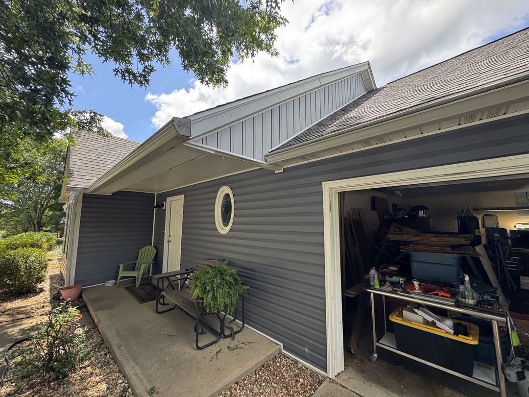 Open workshop door under a board and batten gable in gray siding