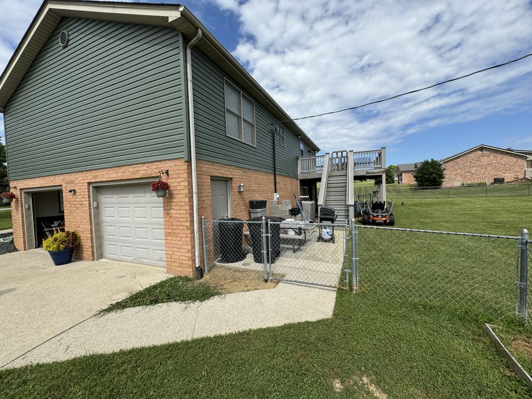 Garage end of a walkout home in green siding with a back deck