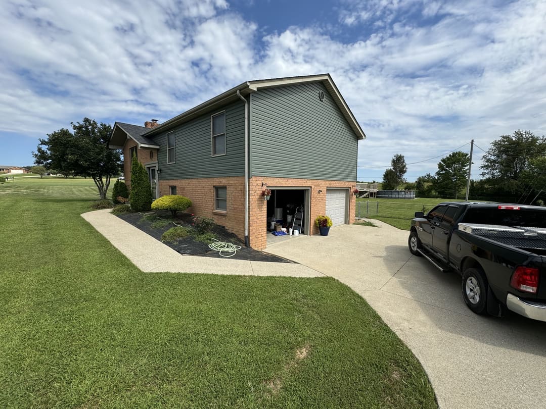 Green siding on a two story walkout home with a brick base