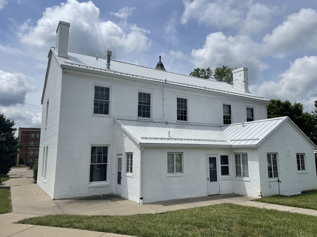 Historic white two story building with a standing seam metal roof