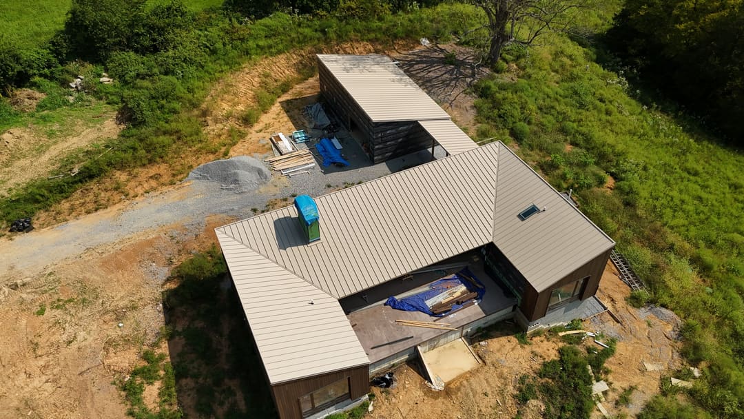 Modern metal roof wrapping a courtyard, materials staged on the deck