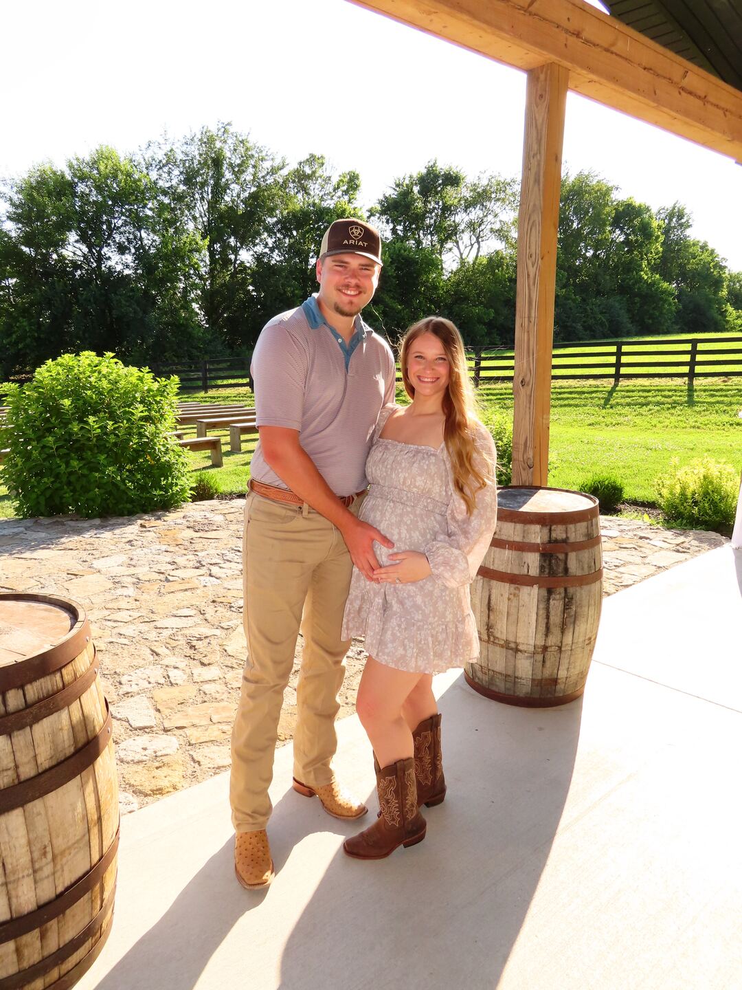 Triston Fitzpatrick and his family on a covered porch, with bourbon barrels and fenced pasture behind them