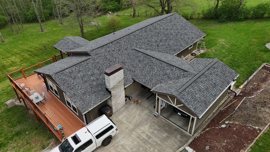 Gray shingle roof over a ranch home and carport with a stone chimney, seen from above