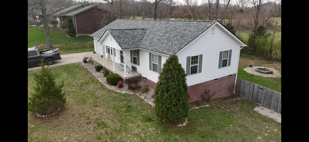 White sided ranch home on a brick foundation with a gray roof